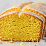 Une tranche de gâteau yaourt citron parfaitement coupée, mettant en valeur sa texture légère et aérienne, surmontée d'un glaçage citronné.