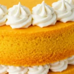 Un gros plan révèle les détails délicats de ce gâteau à l'orange : sa texture moelleuse et les volutes parfaites de crème blanche, un vrai régal pour les yeux et les papilles.
