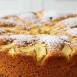 Délicieux gâteau léger aux pommes, avec une croûte dorée et moelleuse, recouvert d'une généreuse couche de sucre glace. Un dessert parfait pour un goûter réconfortant.