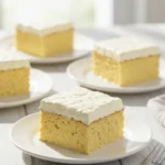 Quatre portions de gâteau nuage sans sucre individuel, présentées sur des assiettes blanches. Le gâteau a une texture spongieuse et est recouvert d'une généreuse couche de crème fouettée blanche. Une fourchette est placée à côté de l'assiette au premier plan.