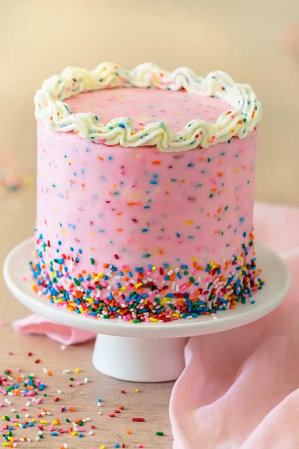 Gâteau anniversaire fille, rose avec des confettis colorés et glaçage blanc.