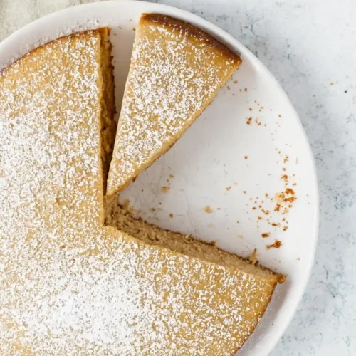 Gateau creme de marron : Vue de dessus d'un gâteau entier, saupoudré de sucre glace, avec quelques parts déjà coupées. Présentation appétissante sur une assiette blanche.