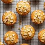 Vue de dessus de financiers gâteaux cuits, refroidissant sur une grille. Les gâteaux sont dorés et garnis d'amandes effilées.