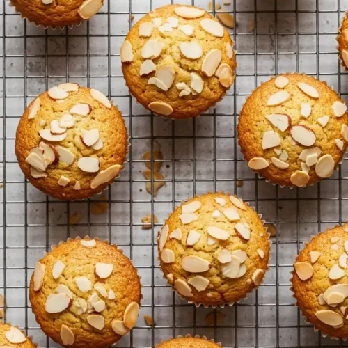 Vue de dessus de financiers gâteaux cuits, refroidissant sur une grille. Les gâteaux sont dorés et garnis d'amandes effilées.