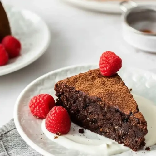 Une part de gateau creusois au chocolat présentée avec des framboises fraîches, pour une dégustation gourmande.