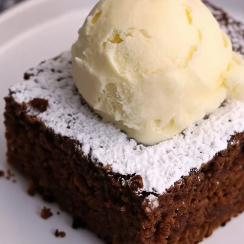 Un délicieux gateau au nesquik moelleux, saupoudré de sucre glace et garni d'une boule de glace crémeuse sur une assiette blanche.