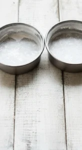 Deux moules à gâteau ronds, préparés avec du papier sulfurisé et de la farine, prêts à accueillir la pâte pour un gateau framboise.