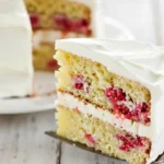 Voici une part de gâteau framboise avec deux couches de crème blanche et de framboises fraîches, posée sur une pelle à tarte.